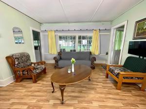 3-Bedroom Cottage #7 - Ambleside في كاوارثا ليك: غرفة معيشة مع أريكة وطاولة +صورتان