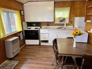 una cocina con armarios blancos y una mesa con flores en Ambleside - 2-Bedroom Cottage #8, en Kawartha Lakes