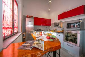 a kitchen with red cabinets and a wooden table at Villa Laura Private Pool and Garden near Lake Maggiore for 9 - Happy Rentals in Besozzo