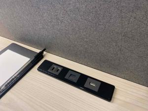 a black digital clock on a table with a pen at Smile Hotel Kanazawa Nishiguchi Ekimae - Vacation STAY 11502v in Kanazawa