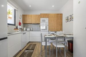 a kitchen with white cabinets and a table and chairs at Orinoco Sunset House I - Private Jacuzzi in Calheta