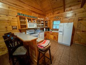 a kitchen with a white refrigerator and wooden cabinets at Ozark Cabin 9 miles to DeGray Lake Private Hot Tub Fishing on Site in Bismarck