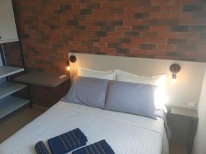 een slaapkamer met een wit bed en een bakstenen muur bij Apartamento SOHO - perto da WEG in Jaraguá do Sul