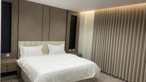a bedroom with a large bed with white sheets and pillows at شقق جولدن إن للشقق المخدومة بجوار مستشفي السعود الالماني in Khamis Mushayt