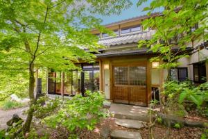a home with a wooden door and some trees at Kanon suisha - Vacation STAY 25508v in Kawaba