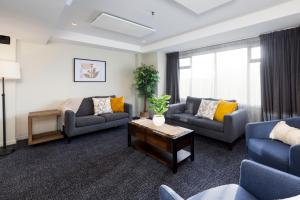 a living room with two couches and a table at Hotel Give in Christchurch