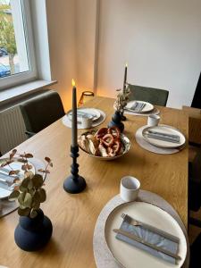 a wooden table with a plate of food and two candles at Lupi Grey - stylish und luxury Apartment in Buchen