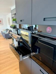 a kitchen with stainless steel appliances and a living room at Lupi Grey - stylish und luxury Apartment in Buchen