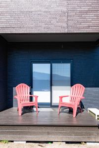 two red chairs sitting on a wooden deck with a window at Soyo in Tsumagoi