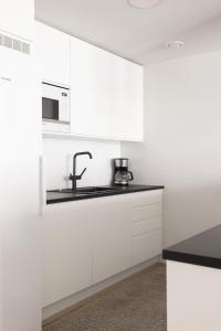 a kitchen with white cabinets and a sink at Modern 2BR apartment W 2 balconies, Metro, Helsinki 15min in Espoo