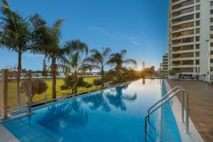 a swimming pool with palm trees and a building at Crowne Plaza Perth by IHG in Perth