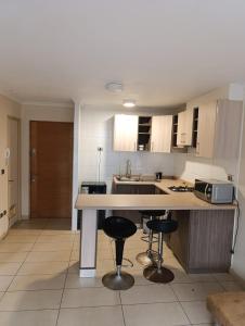 une cuisine avec un comptoir et deux tabourets de bar dans l'établissement Depto 103 barrio universitario con estacionamiento, à Concepción