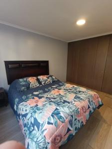 une chambre avec un lit avec un couvre-lit fleuri dans l'établissement Depto 103 barrio universitario con estacionamiento, à Concepción