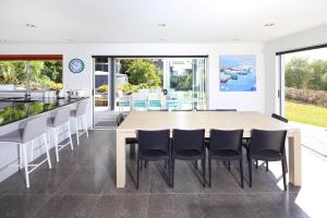 uma cozinha em plano aberto e sala de jantar com uma mesa e cadeiras de madeira em Bella Seven- Waiheke Escapes em Oneroa