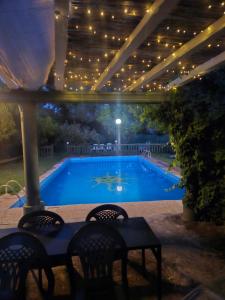 a swimming pool under a pergola with chairs and a table at Finca rural Labriega del hueznar in Cazalla de la Sierra