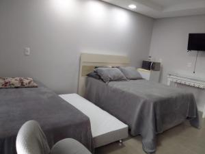 a bedroom with two beds and a chair and a television at StudioD in Passo Fundo