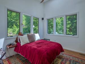 a bedroom with a bed with a red blanket and windows at Windows Over Waterfalls in Hot Springs
