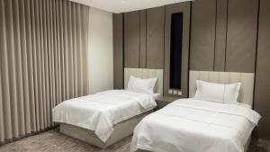 two beds in a room with white sheets at شقق جولدن إن للشقق المخدومة بجوار مستشفي السعود الالماني in Khamis Mushayt +6 photos