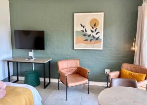 a hotel room with a tv and a desk and chairs at Pont de Val Studio Apartment in Parys