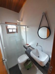 a bathroom with a sink and a toilet and a mirror at 03 Apartamento de praia com ótima localização e piscina in São Sebastião