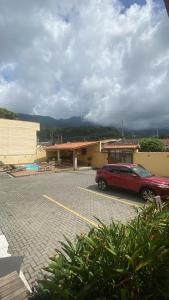 a red car parked in a parking lot in front of a building at 03 Apartamento de praia com ótima localização e piscina in São Sebastião