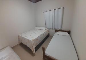 a room with two beds and a window at 03 Apartamento de praia com ótima localização e piscina in São Sebastião