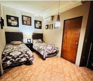 a bedroom with two beds and a wooden door at cuarto acogedor y privado para descansar in Monterrey