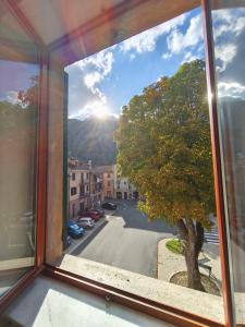a window with a view of a tree and a street at Regina Margherita Apartment in Rocchetta Ligure +2 photos