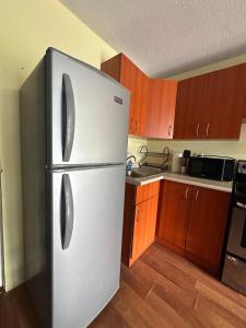 ein weißer Kühlschrank in einer Küche mit Holzschränken in der Unterkunft Histórico 1 Apartment GUA in Estación La Ermita