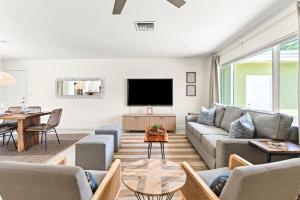 a living room with a couch and a tv at Htd Saltwater Pool! Walk To Beach! Pingpong! Bbq! in West Palm Beach