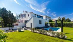 a white house with a yard with a swimming pool at Bonihome Apartments in Punat