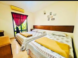 two beds in a bedroom with a window at The 5R Famosa Villa in Kampong Ulu Pegoh +20 photos