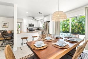 a dining room and kitchen with a wooden table and chairs at Htd Saltwater Pool! Walk To Beach! Pingpong! Bbq! in West Palm Beach