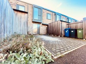 a building with a fence and some trash cans at Superb House Sleeps 7 parking in Cambridge in Trumpington