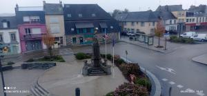 a statue in the middle of a street with buildings at centre ville confortable in Gourin