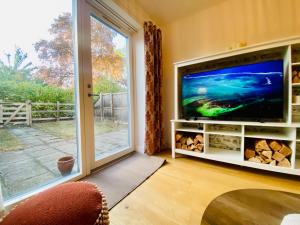 a living room with a tv and a large window at Superb House Sleeps 7 parking in Cambridge in Trumpington