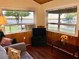 Sala de estar con 2 ventanas, sofá y mesa en 2-Bedroom Cottage #11 - Ambleside, en Kawartha Lakes