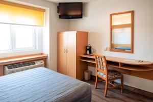 1 dormitorio con escritorio, 1 cama y espejo en Intercity Zapopan, en Guadalajara
