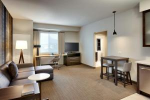 a living room with a couch and a table and a desk at Residence Inn by Marriott Madison in Madison
