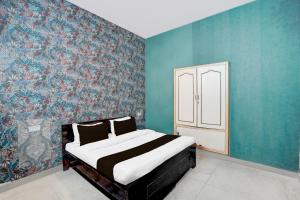 a bedroom with a bed and a blue wall at Super Hotel O The Comfort in Kānpur