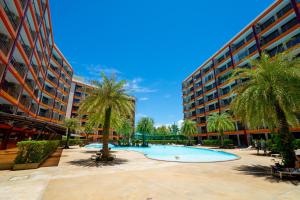 un patio con palmeras y un edificio grande en The Signature Suite, en Ban Mai Salae