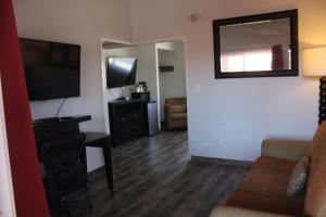 a living room with a couch and a desk and a television at Sunset Inn in Costa Mesa +3 photos