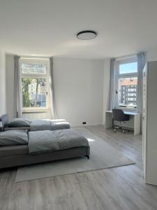 a bedroom with a bed and a desk and two windows at Modernes Apartment Nähe Cologne und Düsseldorf in Niederdorla