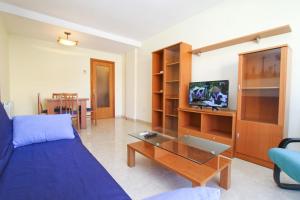 een woonkamer met een blauwe bank en een tv bij Roura 2 Planetcostadorada in La Pineda