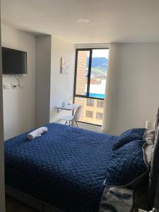 Estación El Saltoにあるhermoso apto para estrenar Unicentro calle 27のベッドルーム1室(青い掛け布団、窓付)