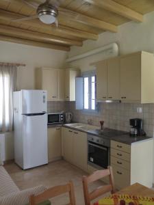 a kitchen with a white refrigerator and a table at Kaminaki Amorgos in Órmos Aiyialís