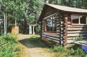 a log cabin in the woods with a window at Country Rustic Loghouse at Teepee Meadows in Valemount