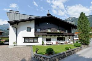 a white and black house with a grass yard at Alpin Hotel Garni Eder - Private Living in Mayrhofen