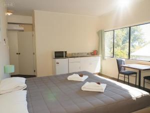 a bedroom with a bed with two towels on it at Drury Motor Lodge in Drury