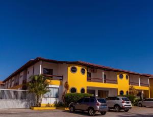 a yellow and white building with cars parked in a parking lot at Andimar Hotel in Porto Seguro